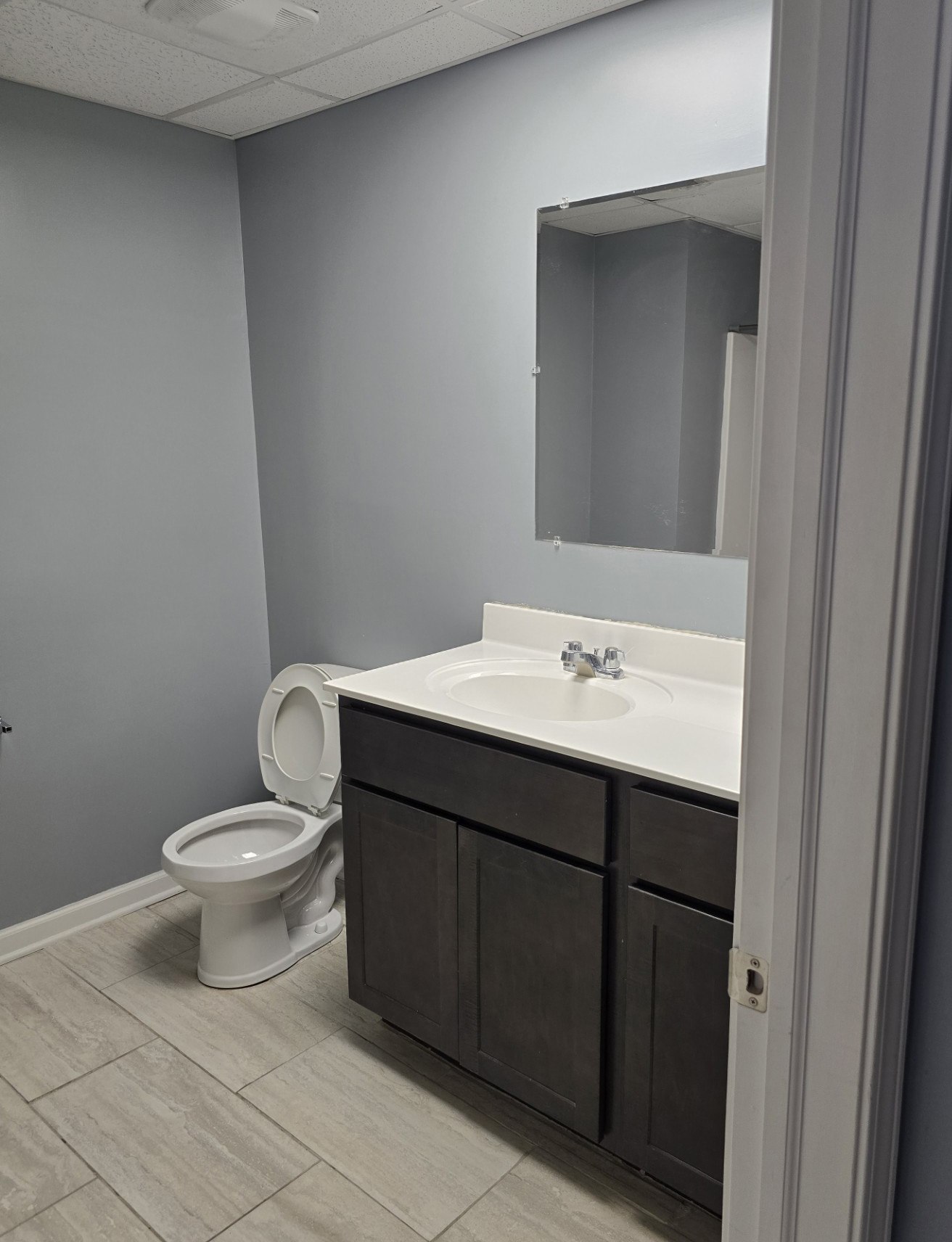 A bathroom with a toilet, sink, and mirror.